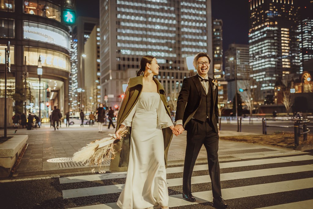 ウェディングドレスとタキシードを着て東京駅を歩くふたり