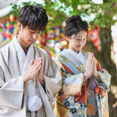 カラフルなお守りが可愛いお寺でお参りするお二人