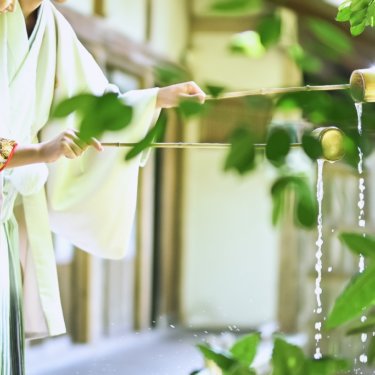 縁側で打ち水をする新郎新婦