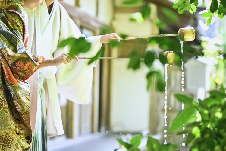 縁側で打ち水をする新郎新婦