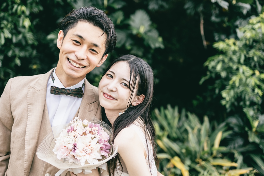 沖縄の緑をバックに笑顔の夫婦