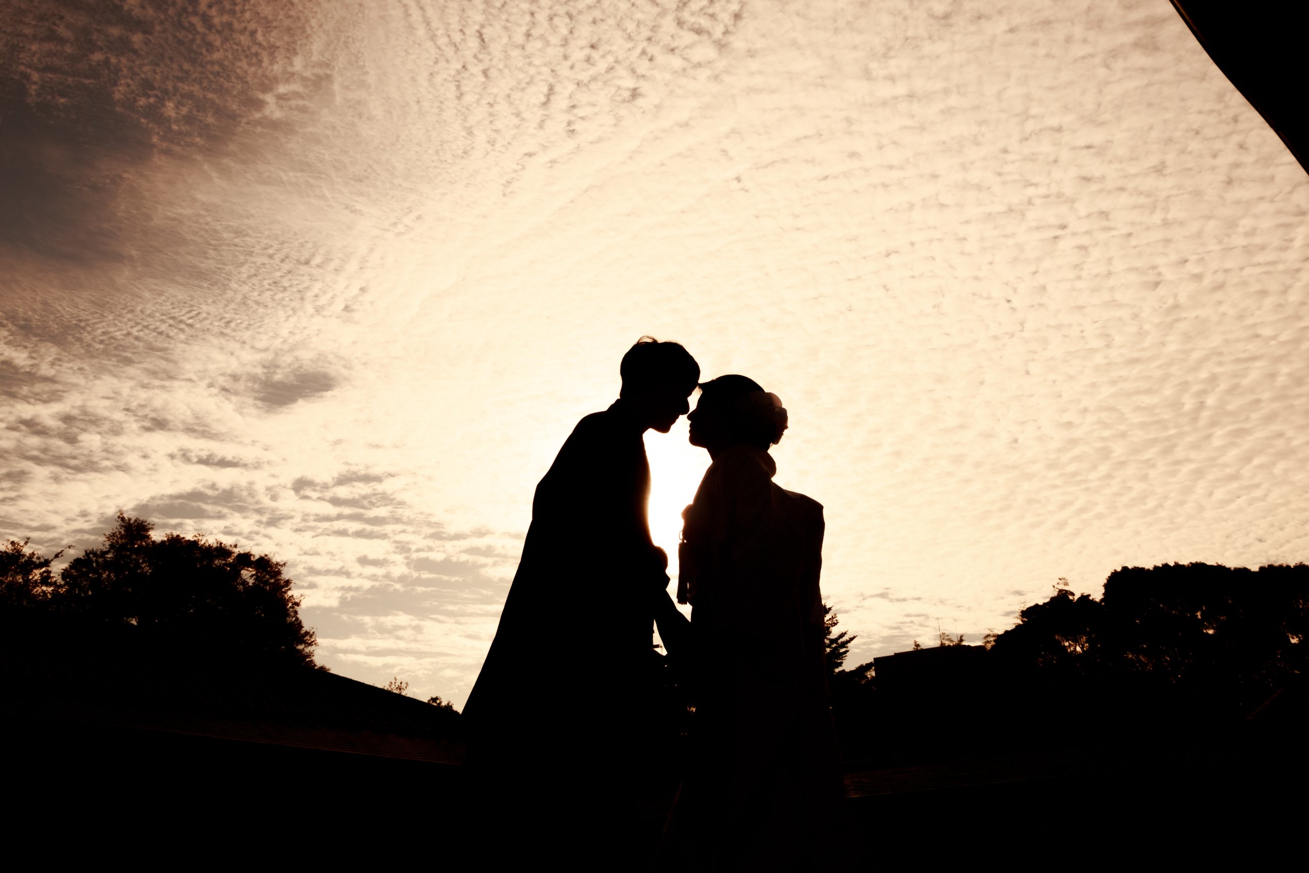 夕日をバックに見つめ合う新郎新婦