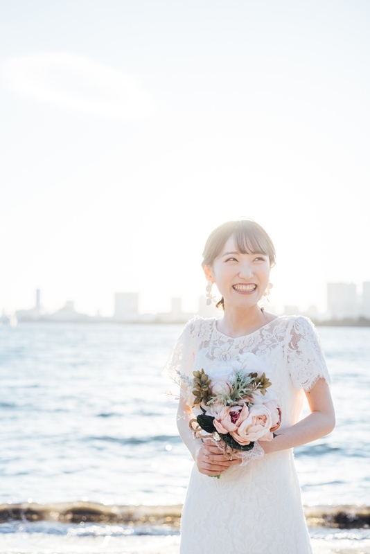 お台場海浜公園の砂浜でトレーンが美しく広がるウェディングドレス姿の花嫁、青い海と白砂が映えるシーン