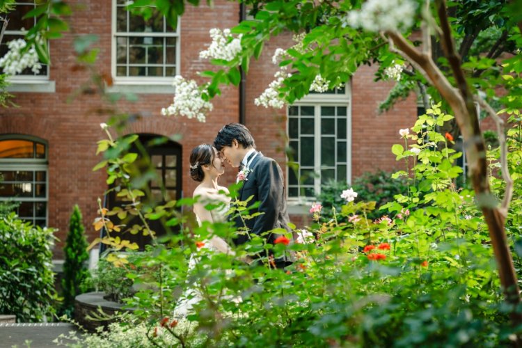 緑と花々に囲まれ寄り添う新郎新婦のウェディングフォト