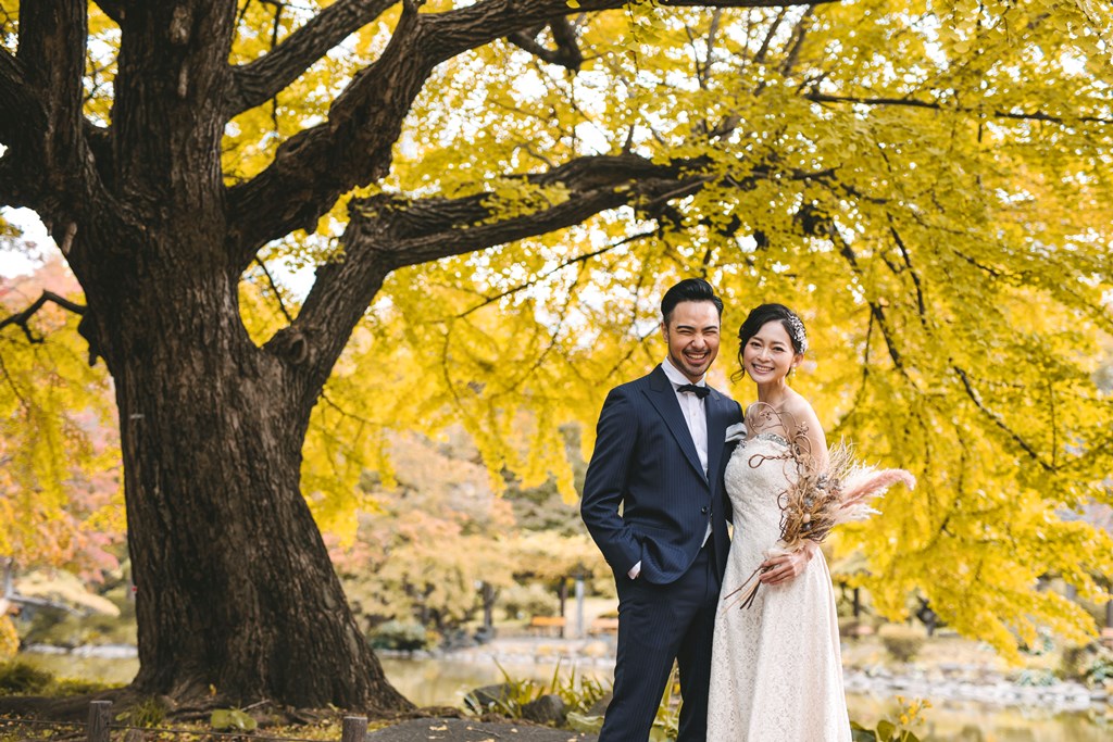 日比谷公園の紅葉シーズンでのウェディングドレス前撮り、赤・橙・黄の紅葉と白いドレスが美しいコントラストをなす都心の秋らしい一枚