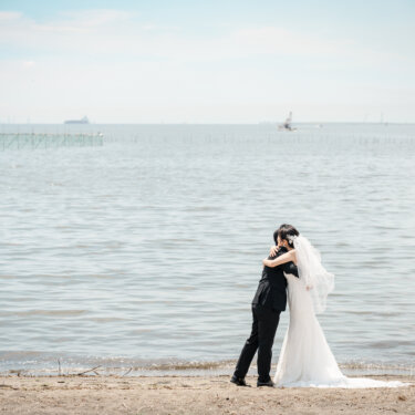 東京湾の水平線を背に、波打ち際で抱き合う新郎新婦。葛西の海の広さが伝わるウェディングフォト