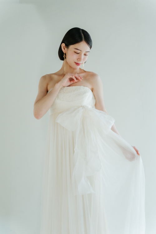 透け感のあるチュールスカートのエンパイアドレスを着た花嫁の全身。やわらかなシルエットのウェディングドレス