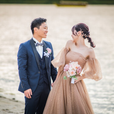 お台場の砂浜でブーケを手に見つめ合う、ネイビーのタキシードの新郎とパフスリーブのカラードレスの花嫁の前撮り