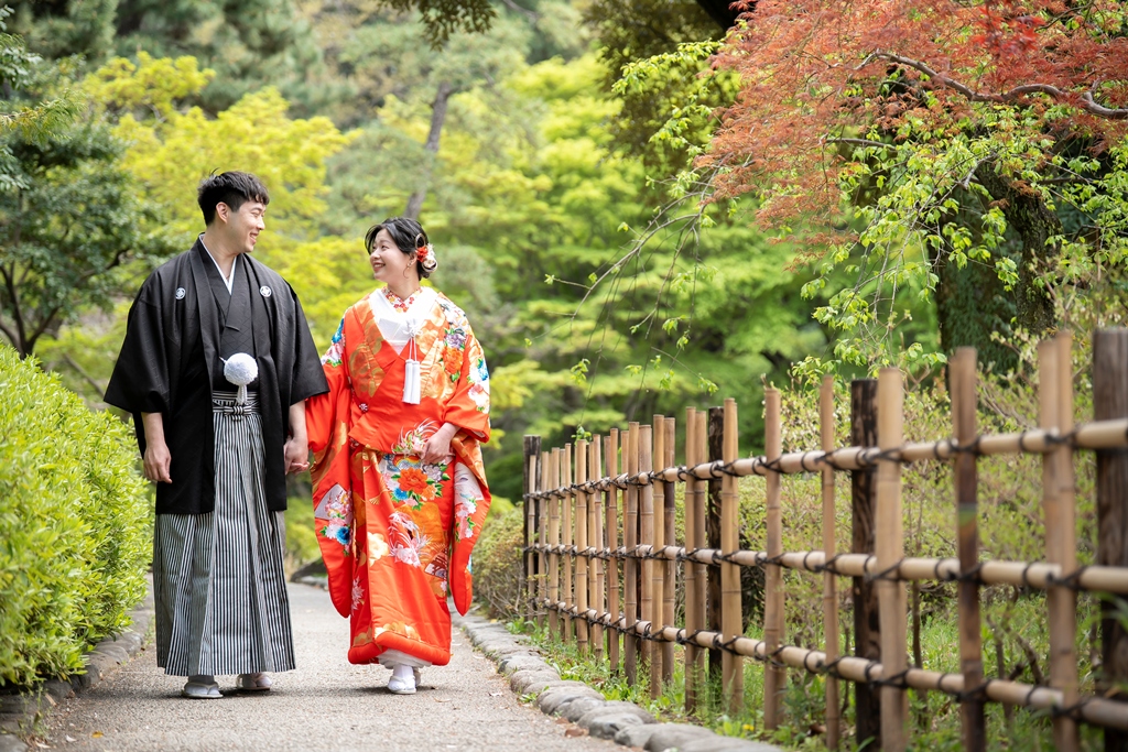 甘泉園公園の木造の東屋に腰かけて色打掛の袖の柄を膝の上に重ねた新婦の写真