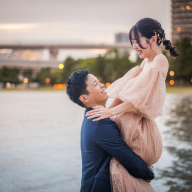 夕暮れの街の灯りを背に、カラードレスの花嫁を抱き上げて見つめ合う新郎。お台場海浜公園のフォトウェディング