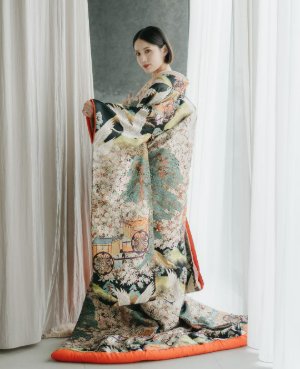 黒と若草色の地に花々を描き、赤いふきがのぞく色打掛を両手で広げる花嫁の和装前撮り（衣装番号DR01）