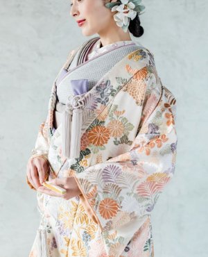 淡いオレンジに花模様が広がる色打掛「陽音華文」をまとい、大ぶりの髪飾りを付けた表参道店の和装前撮りの花嫁（衣装番号YMOS14）