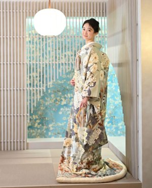 セージグリーンに大柄の花を描いた近代色打掛「翠華絢爛」で、丸い照明の和室に立つ花嫁の和装前撮り（衣装番号YMOS13）