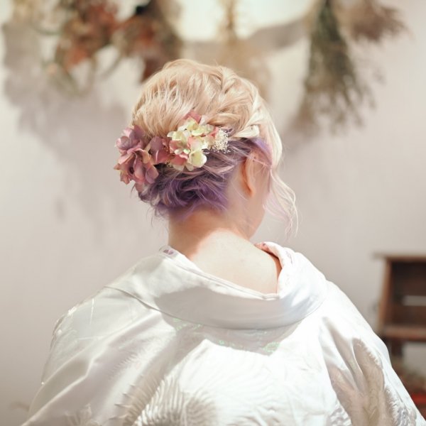 ピンクとパープルのカラーヘアに花の髪飾りを添えたアップスタイル。白無垢に合わせる個性的な前撮りのヘアアレンジ