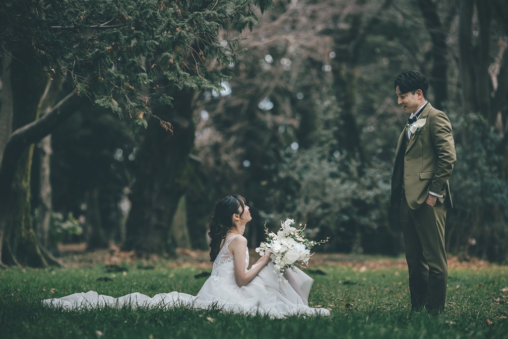 砧公園の芝生広場でウェディングドレスを着た前撮り写真、広い空間の中でドレスのシルエットが際立つ