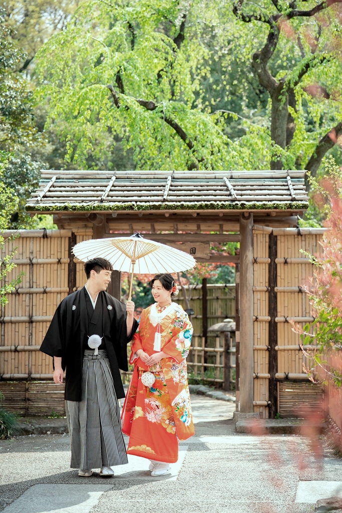 甘泉園公園の緑豊かな庭園で赤い色打掛の鮮やかな色が映える新婦の写真