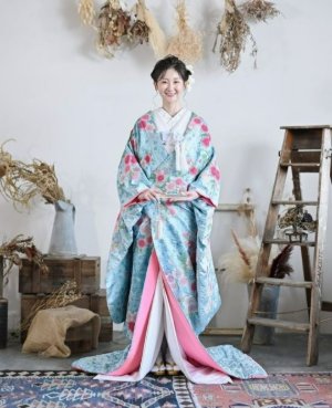 スカイブルーの地にピンクの花が咲く色打掛「桃翠」をまとい、ドライフラワーの部屋に立つ表参道店の和装前撮り（衣装番号DB01）