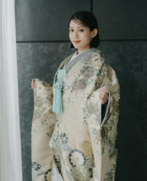 白地にグリーンとシルバーグレーの花々が咲く色打掛「蒼華優雅」を羽織り、ピンクベージュの裏地を見せる表参道店の和装前撮り（衣装番号DMOS17）
