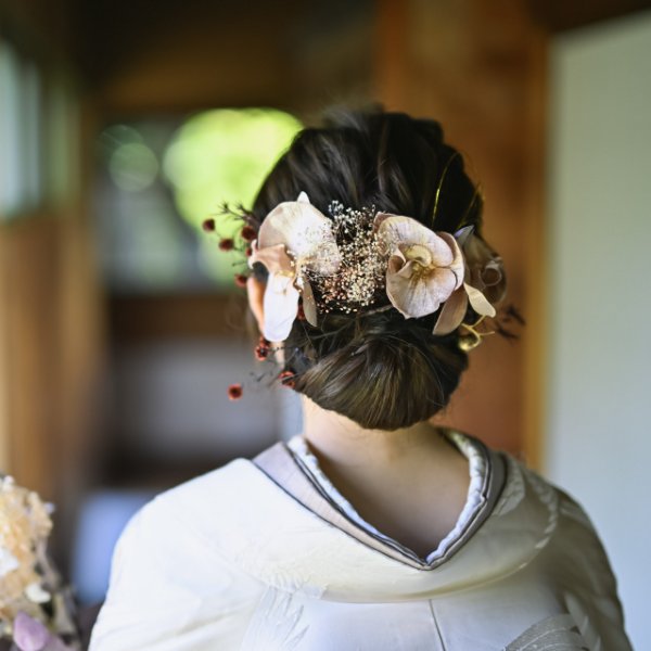 胡蝶蘭の髪飾りを添えた低めのシニヨン。白無垢の花嫁の後ろ姿を和室で撮った和装前撮りのヘアアレンジ