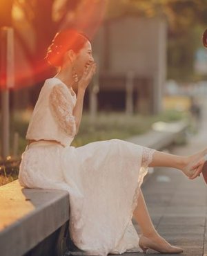 総レースのスカートにピンクのトップスを合わせたセパレートのウェディングドレスで、夕日の差す屋外に座る花嫁の前撮り（衣装番号DB01）