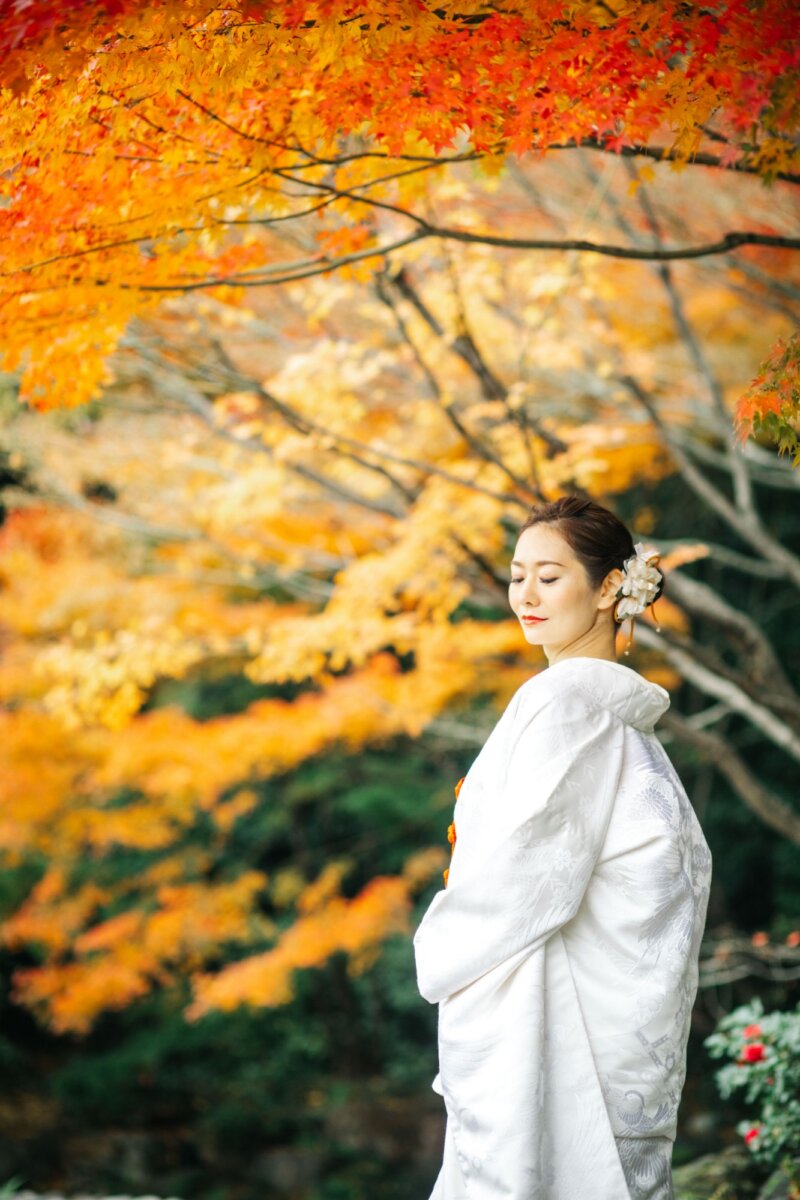橙と赤のもみじの下で佇む白無垢の花嫁。紅葉ロケーションフォト